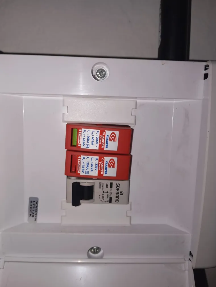 Quadro de proteção aberto, com dois dispositivos de proteção contra surtos, um deles com a janela de status vermelha