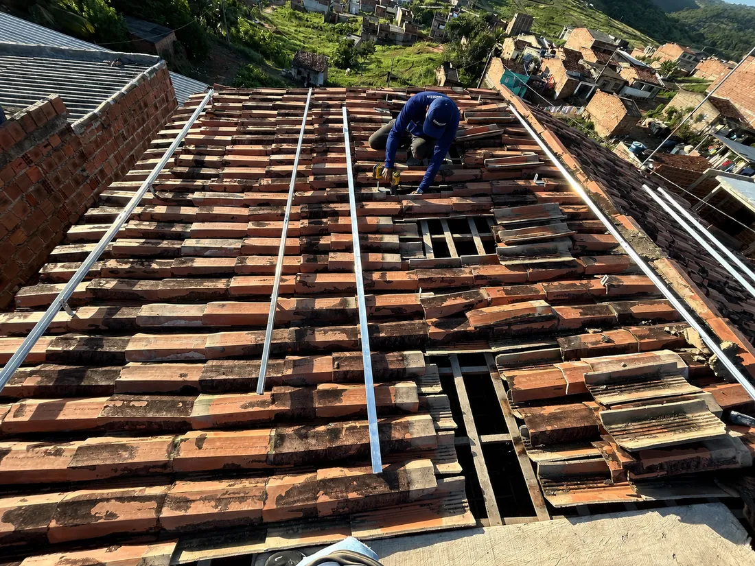 Instalador da Progress fixando os trilhos de alumínio no telhado com as telhas removidas